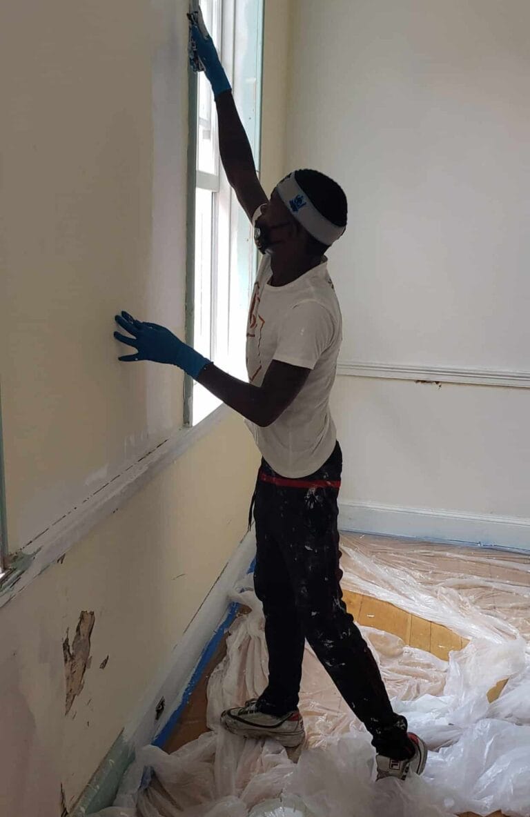 A person paints a wall in a historic building.