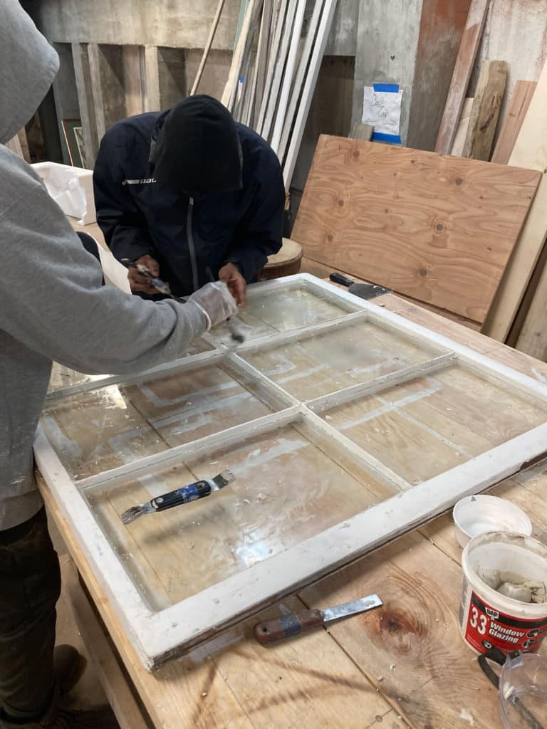 A person works on striping a window on a table.