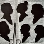 Six small black silhouette portraits on a piece of white cloth, along with a silver pair of scissors.