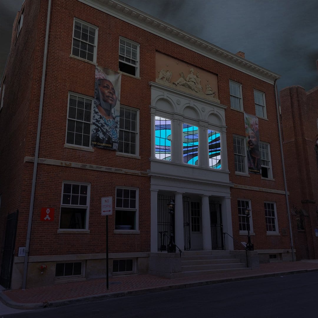 The Peale building at night with its second floor windows illuminated by a bluish light.