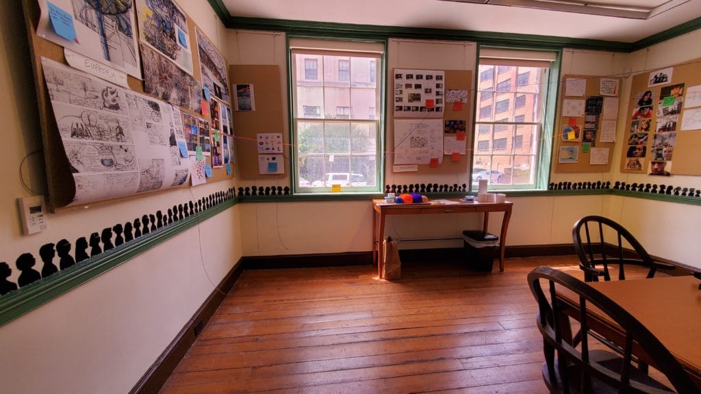 A room in a historic building that shows a green chair rail and small, back silhouette portraits running along the chair rail.
