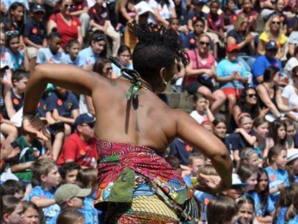 A woman dances in front of a large crowd of people.