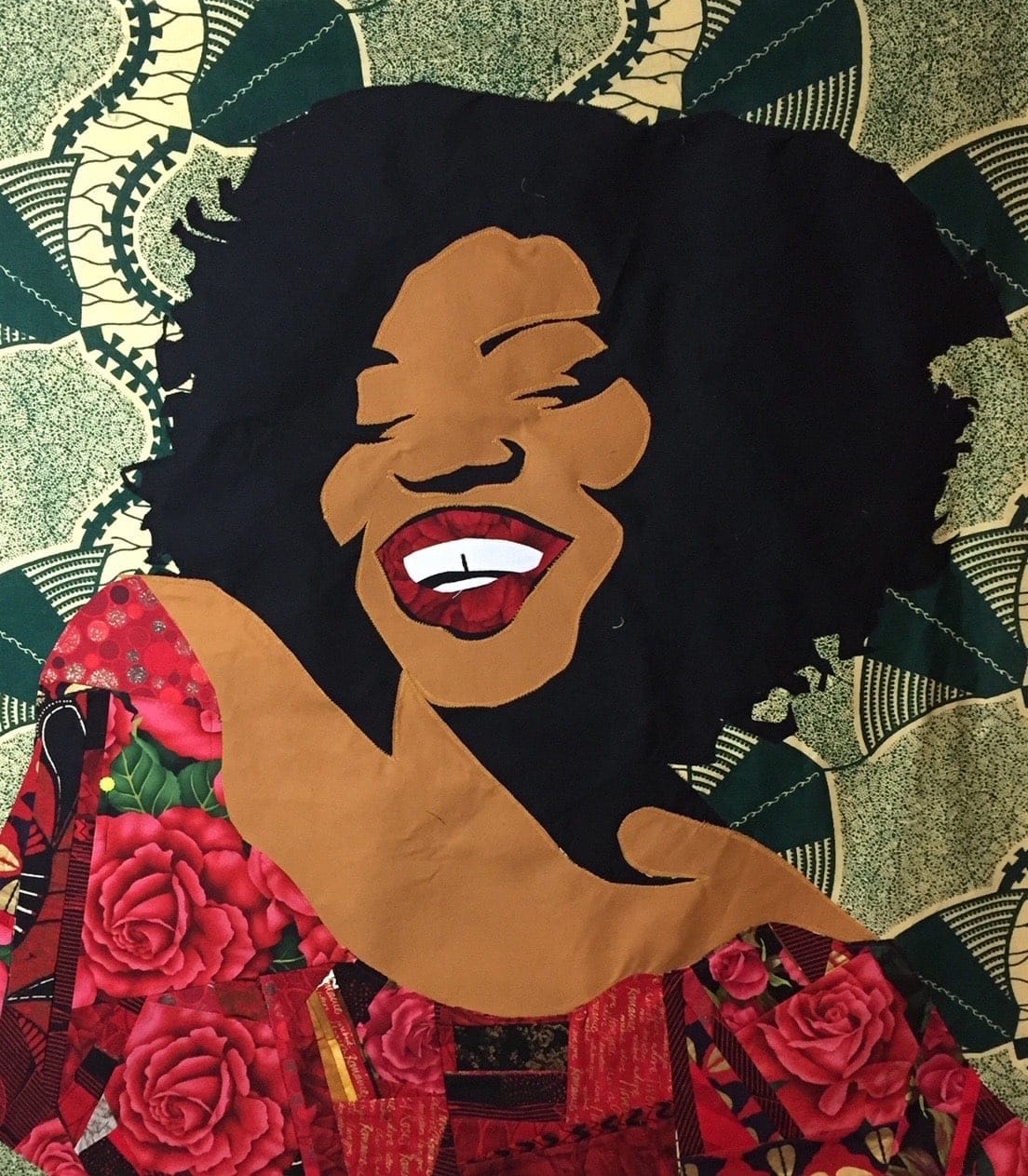 A woman's face--with a broad white smile--is woven into a detailed quilted with a green background.