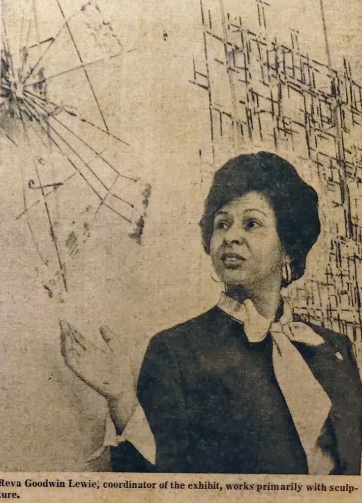 A woman with a 1960s hair style motions up to artwork on a wall in a vintage newspaper article.