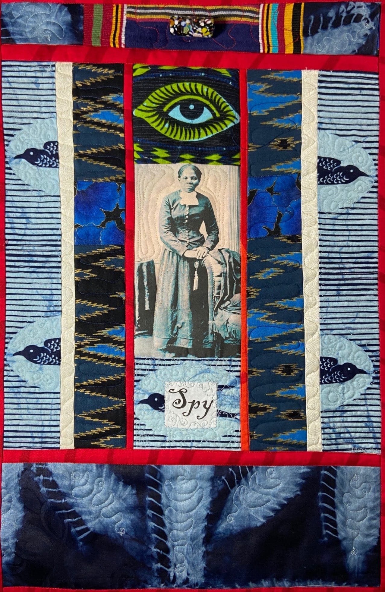 A blue, black, red, and white quilt that features a portrait of Harriet Tubman.