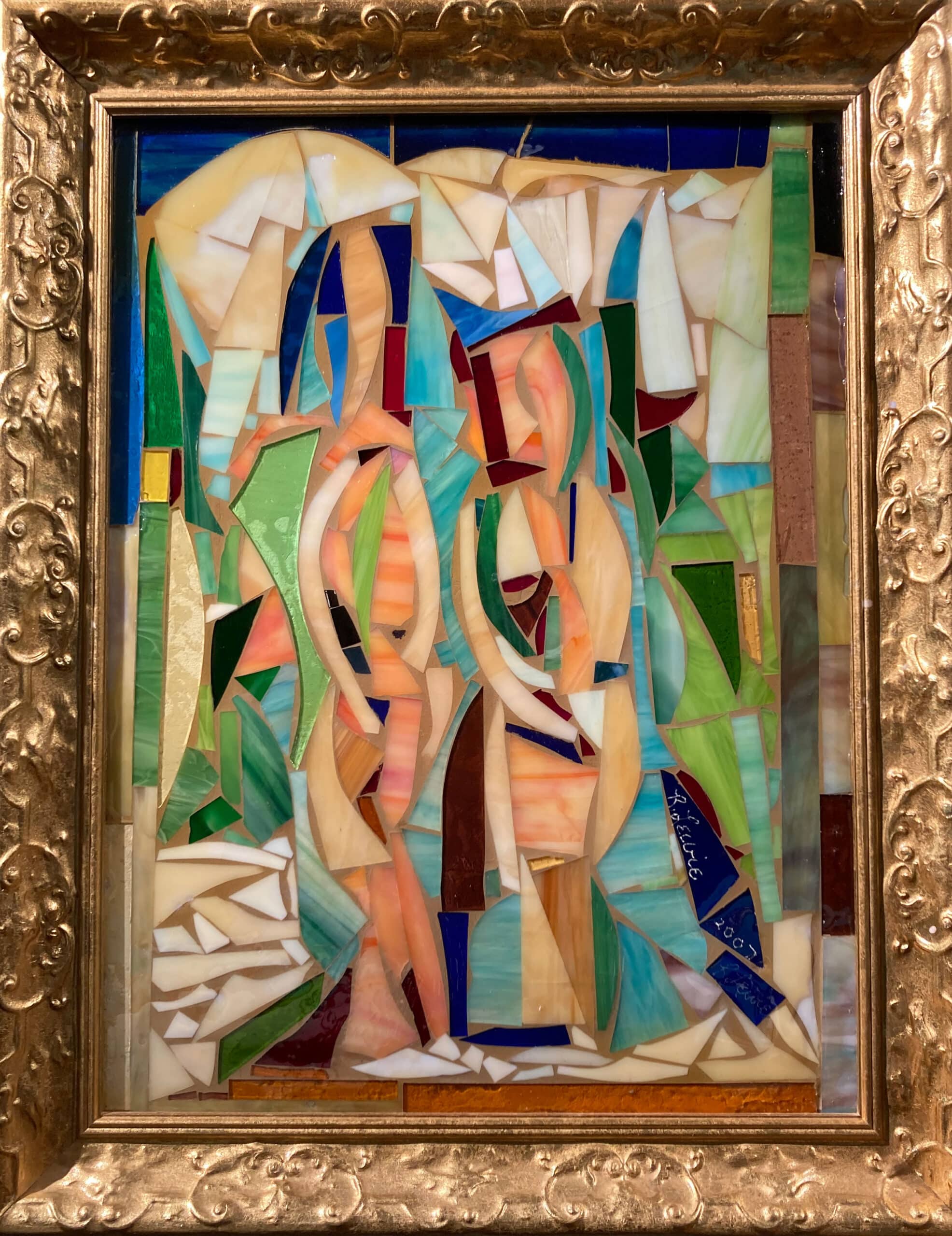 A work of art in a gilded frame that displays sharply angular pieces of brown, red, and blue glass.