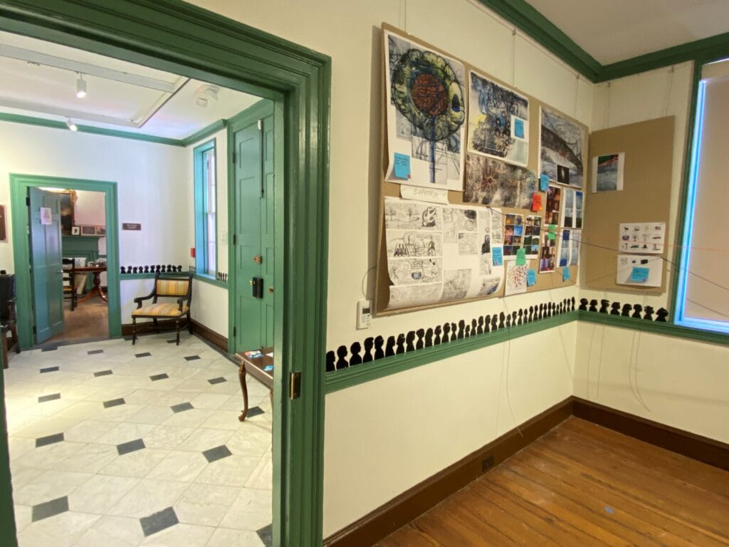 A museum gallery that features small black silhouette portraits in a room that looks into a foyer.