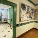 A museum gallery that features small black silhouette portraits in a room that looks into a foyer.