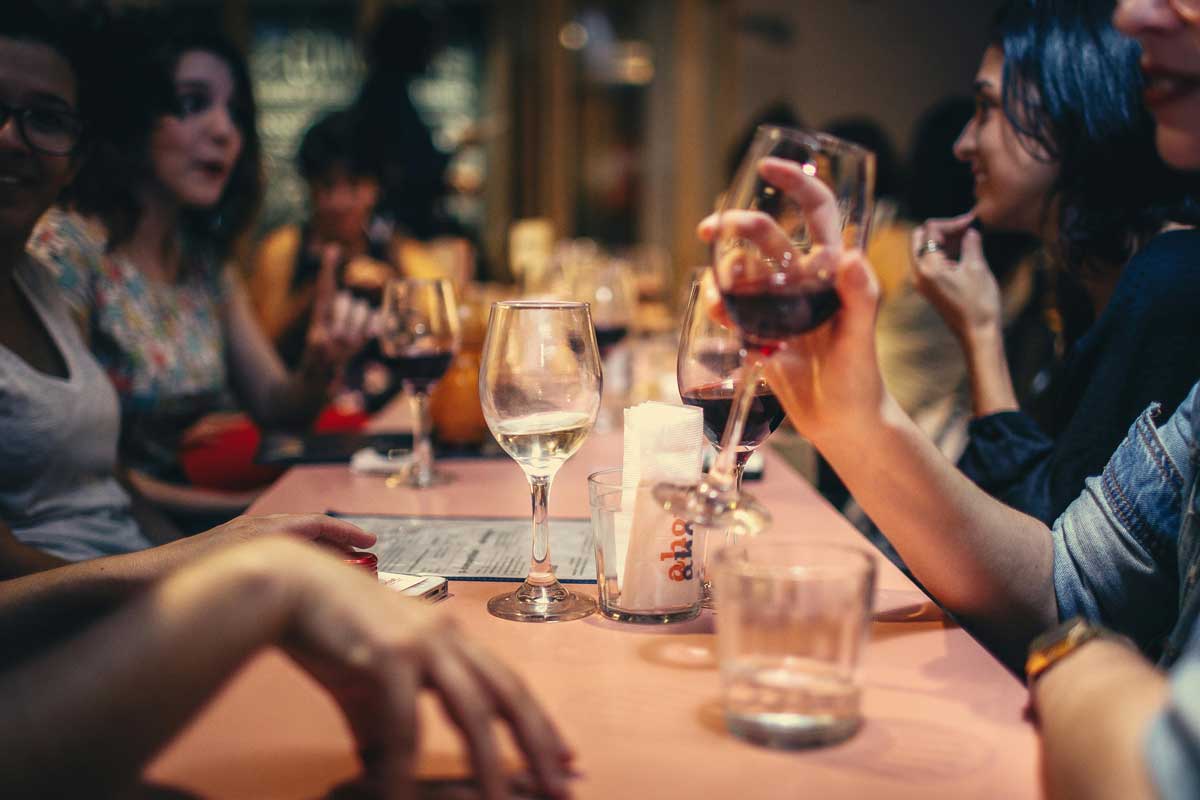 A group of women sit at a table and drink wine.