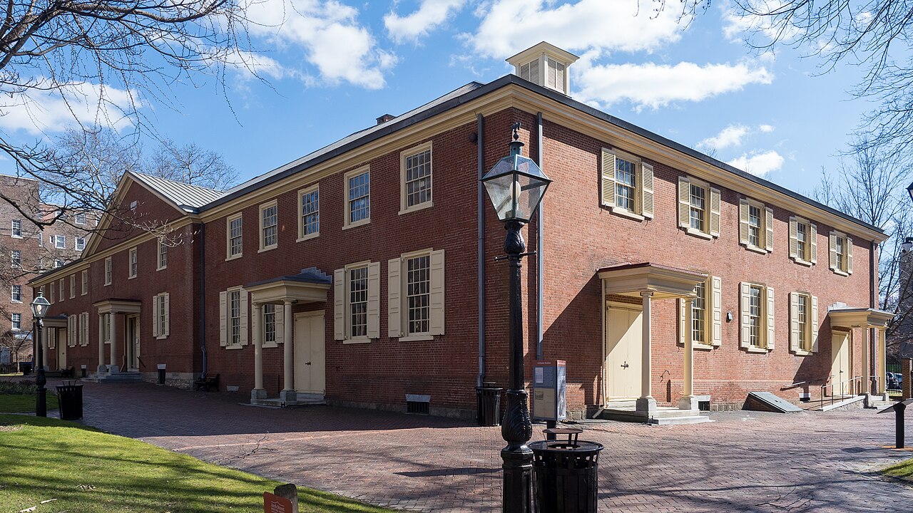 An all-brick historic Quaker meeting house with shutters and a porch.