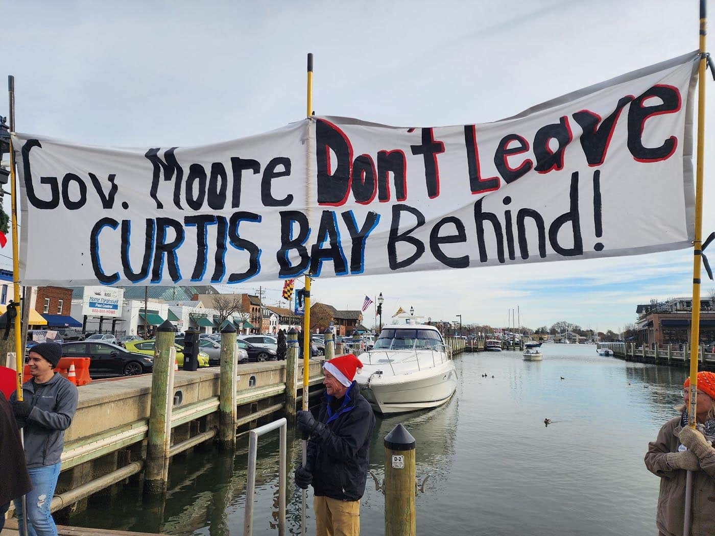 People hold a banner that says, Gov. Moore, Don't Leave Curtis Bay Behind.