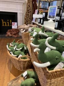 A group of baskets that has green stuffed mastodons in them.